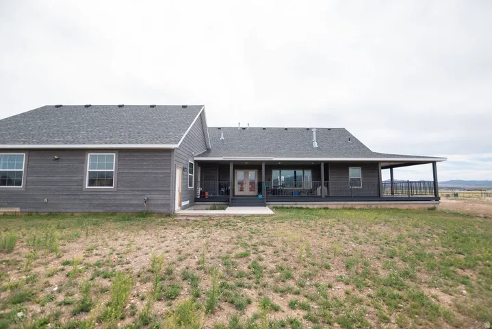 Ranch-style exterior featuring gray horizontal siding, an extended covered porch with railing, and a gray shingle roof