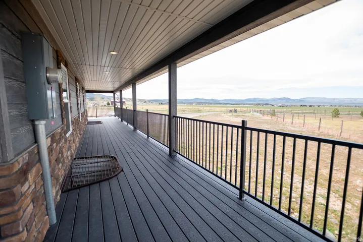 Spacious covered porch with dark composite decking, column supports, and a black metal railing