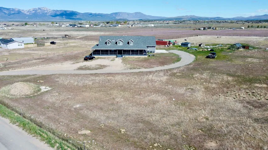 Expansive property with a central residence featuring a wraparound porch, dormer windows, and a shingle roof