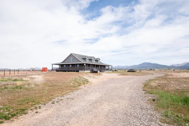 Ranch-style residence featuring a prominent covered wrap-around porch and a gravel driveway