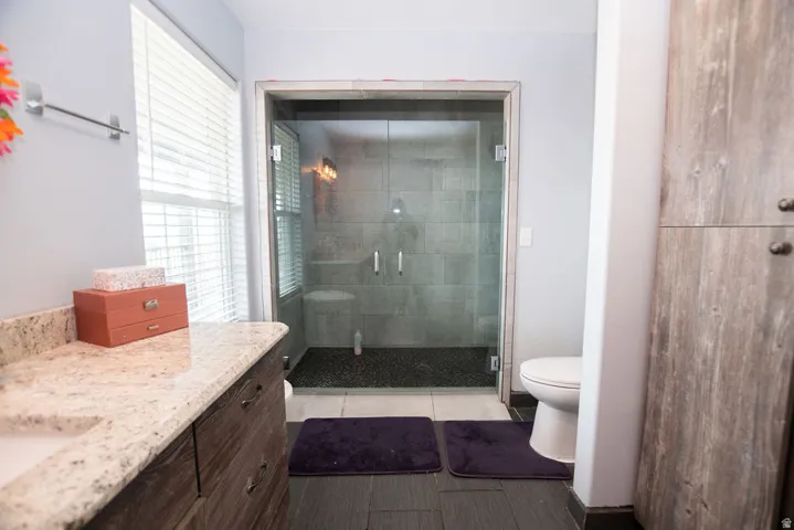 Glass-enclosed shower with dark pebble-finish flooring and subway tile surround