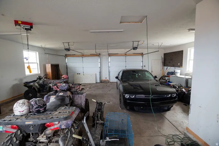 Spacious garage featuring two overhead doors, a concrete floor, and multiple windows providing natural light