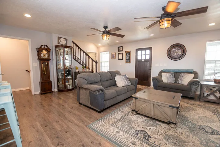 Open-concept living space with wood-finish flooring, recessed lighting, and multiple ceiling fans