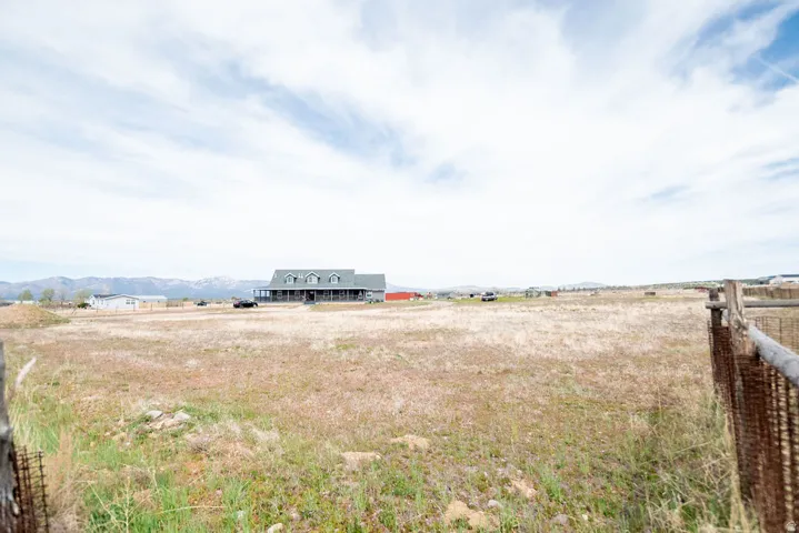 Expansive open fields surrounding a ranch-style residence with a covered front porch and multiple dormer windows