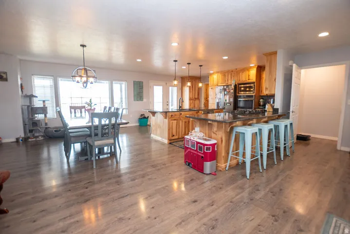 Open-concept kitchen and dining area featuring wood-finish flooring, recessed lighting, and a kitchen island with stone countertop