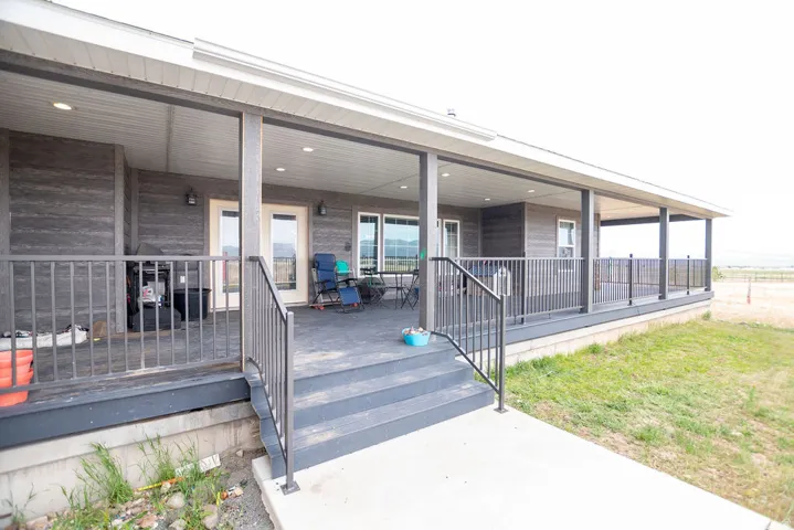 Expansive covered porch featuring a composite deck, dark gray railing system, recessed lighting, and wall-mounted exterior fixtures