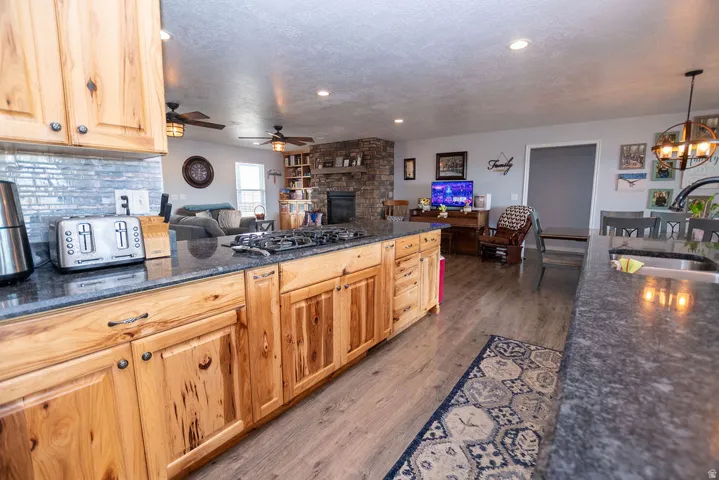 Kitchen island with an integrated gas cooktop and deep basin sink, wood-finish flooring, and natural wood cabinetry