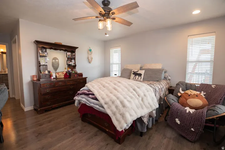 Spacious room featuring wood-finish flooring, light gray walls, and a ceiling fan with integrated lighting