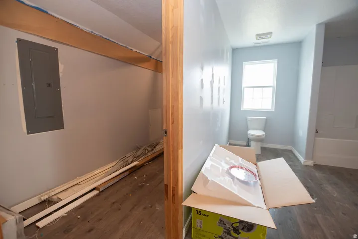 Bathroom featuring a white toilet, single window, and a white bathtub with shower surround