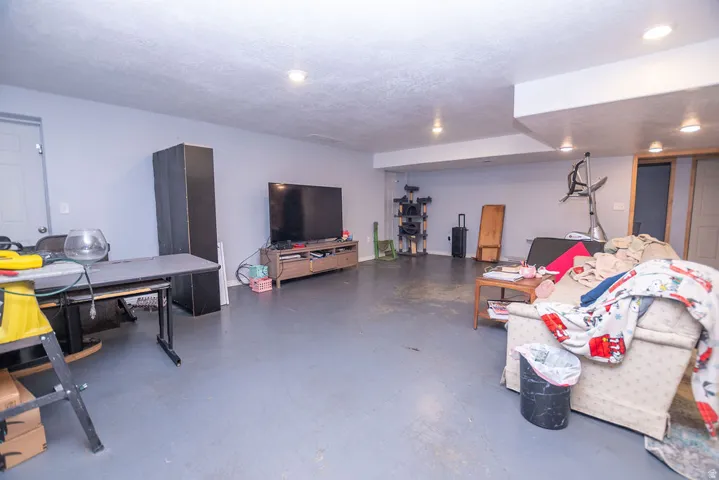 Spacious lower level featuring gray painted flooring, recessed lighting, and a white paneled door