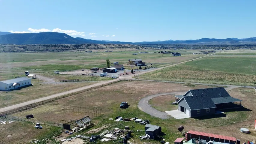 Expansive rural property featuring multiple structures, a circular driveway, and mountainous backdrop
