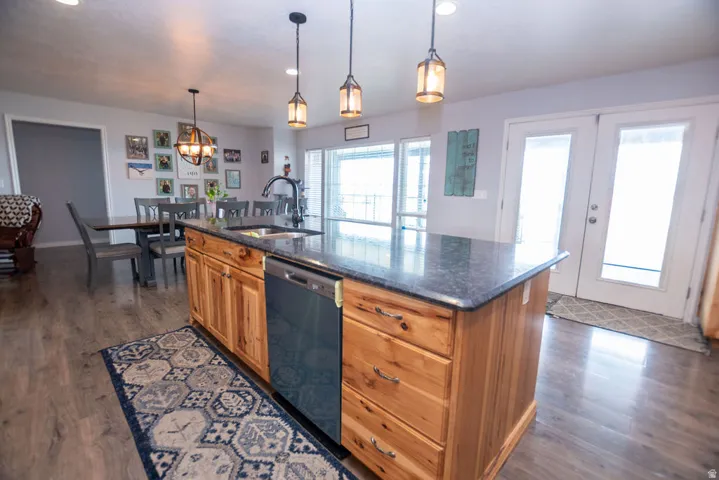 Kitchen island featuring a dark countertop, an undermount sink with a gooseneck faucet, and integrated dishwasher