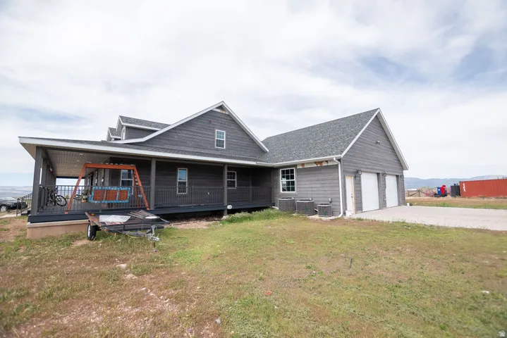 Gray-toned exterior featuring horizontal siding, a covered front porch with a railing, multiple gables, and a two-car garage with white doors