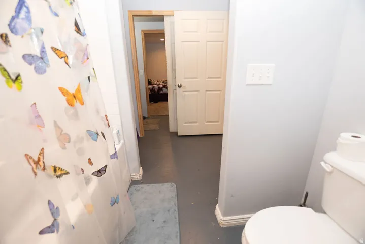 Bathroom featuring a white toilet, light gray walls, and base molding