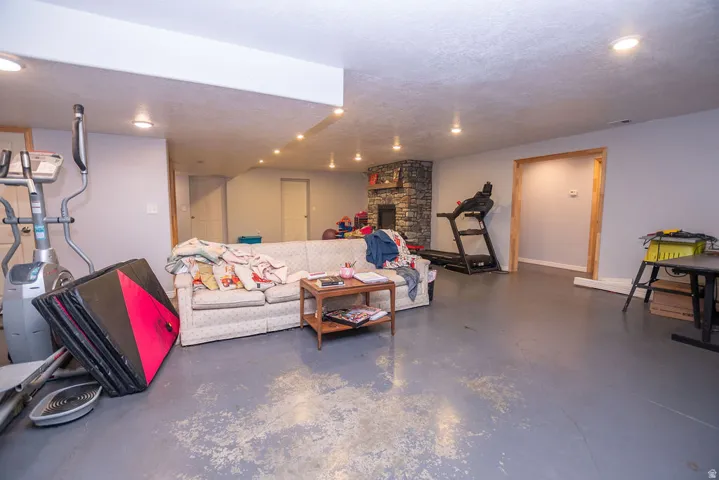 Expansive finished lower level featuring a stone-clad fireplace and recessed lighting