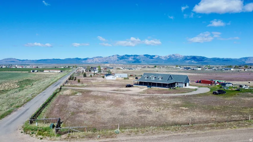 Ranch-style residence featuring a prominent covered front porch, an attached two-car garage, and a gravel driveway