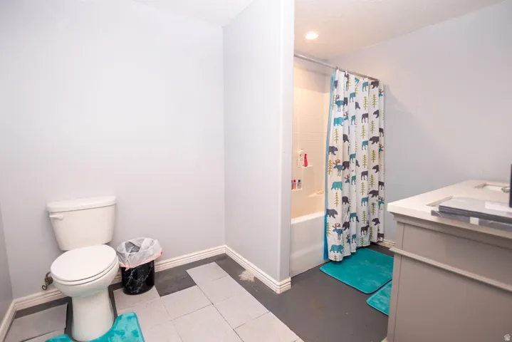Bathroom featuring a white toilet, built-in vanity with a light countertop, a shower-over-tub combination, and gray walls