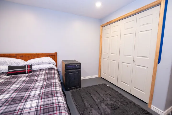 Bedroom featuring light gray walls, recessed ceiling lighting, and a white bi-fold closet door with natural wood-finish trim