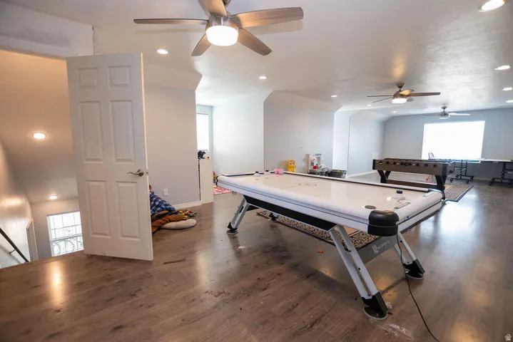Spacious upper-level room featuring wood-finish flooring, recessed lighting, and multiple ceiling fans