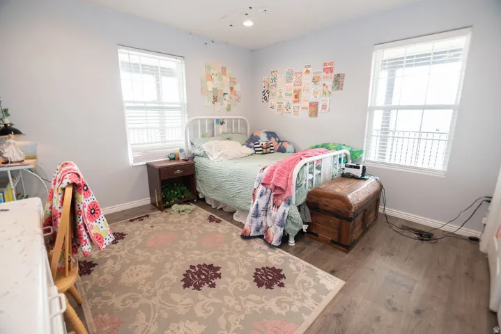 Room featuring wood-finish flooring, light gray wall paint, and two windows with white blinds
