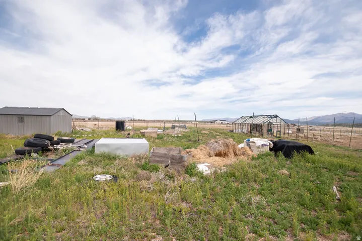 Expansive outdoor space featuring a utility shed, a greenhouse structure, and a fenced perimeter
