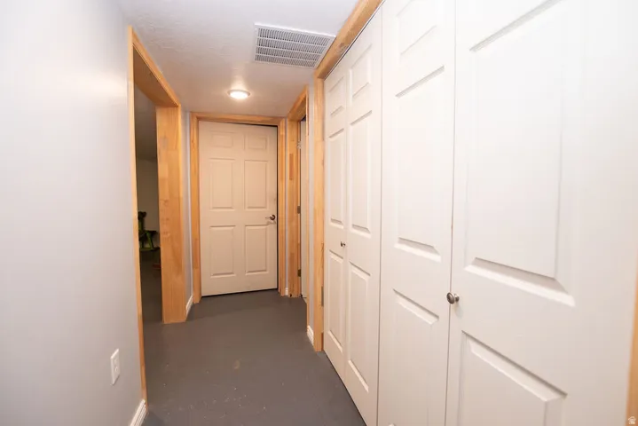 Hallway featuring light wood-finish door frames and baseboards, contrasting with light gray walls and dark gray flooring