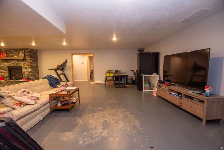 Spacious room with a stone-clad fireplace and a painted concrete floor
