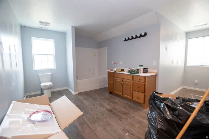 Bathroom featuring wood-finish flooring, a white porcelain toilet, and a white tub/shower combination