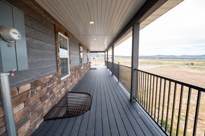 Expansive covered porch featuring durable composite decking and a black metal railing