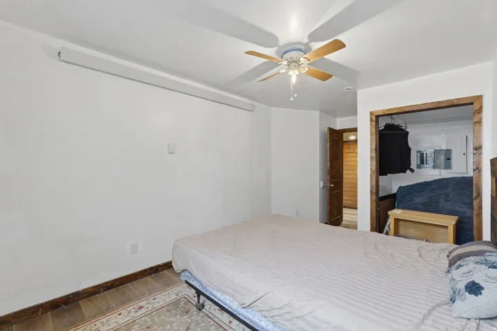 Room featuring wood-finish flooring, a ceiling fan, and white painted walls