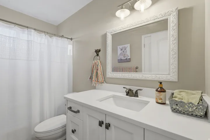 Modern vanity featuring a white countertop with an integrated sink, dark hardware, and a framed mirror