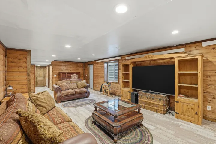 Recessed lighting illuminates a spacious room featuring plank wood-finish flooring and extensive wood paneling