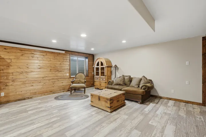 Spacious room featuring light wood-finish flooring, recessed lighting, a horizontal plank accent wall, and a window with blinds