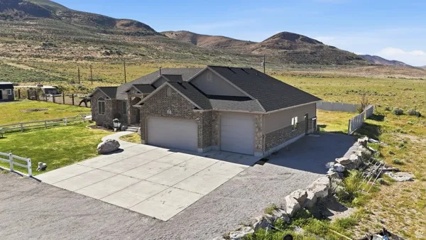 Stone and stucco exterior residence featuring a two-car garage, an additional single-car garage, and a concrete driveway