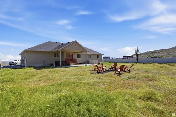 Expansive backyard with a covered patio, red exterior doors, and a partial privacy fence