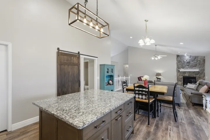 Kitchen island with granite countertop, wood-finish flooring, and a sliding barn door