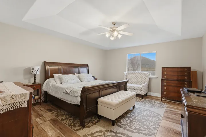 Spacious room featuring a tray ceiling, wood-finish flooring, and neutral wall tones