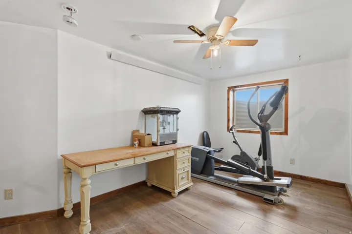 Interior room featuring wood-finish flooring, white walls, and a window with wood trim