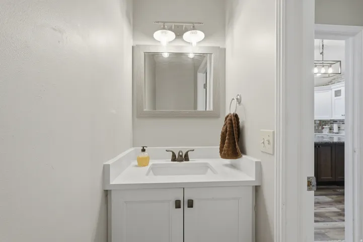 Contemporary bathroom vanity featuring a white countertop, undermount sink, and bronze-finish faucet