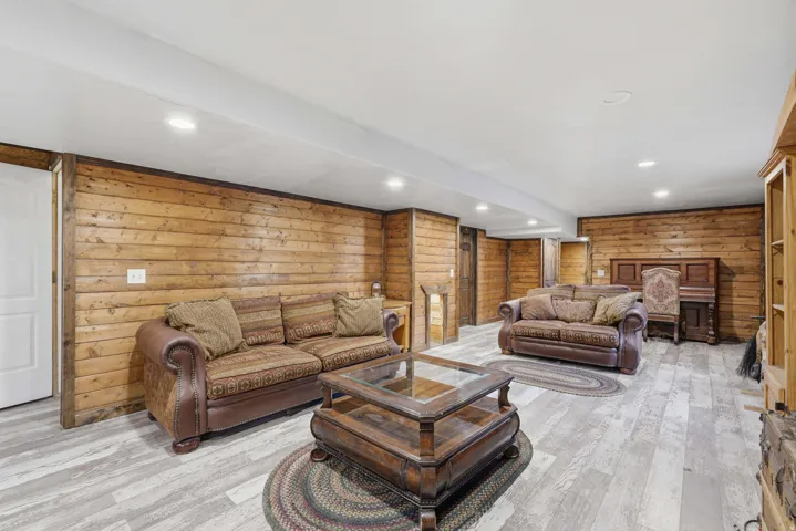 Spacious room featuring wood-finish wall paneling, light wood-finish flooring, and recessed ceiling lighting