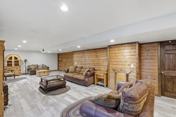 Spacious room featuring wood-finish flooring, recessed lighting, wood paneling, and a dark wood paneled door