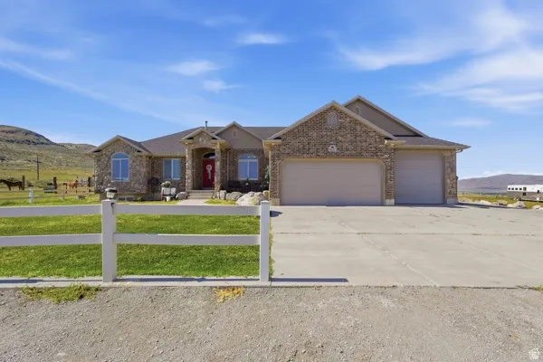 Stone and brick-clad ranch-style residence featuring a prominent red entry door, a two-car garage with an additional single-car garage, and a concrete driveway