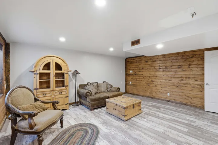 Spacious room featuring wood-finish flooring, recessed lighting, and a prominent wood-paneled accent wall