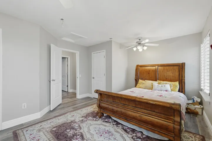 Spacious room featuring wood-finish flooring, light grey wall paint, and white baseboards