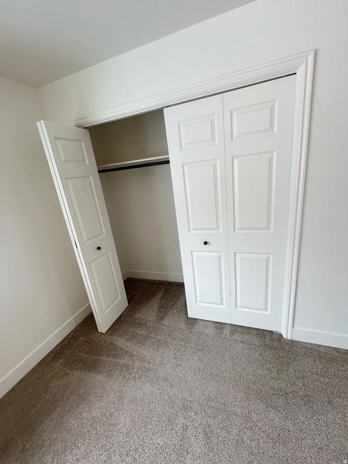 Integrated closet with bi-fold panel doors and black knob hardware