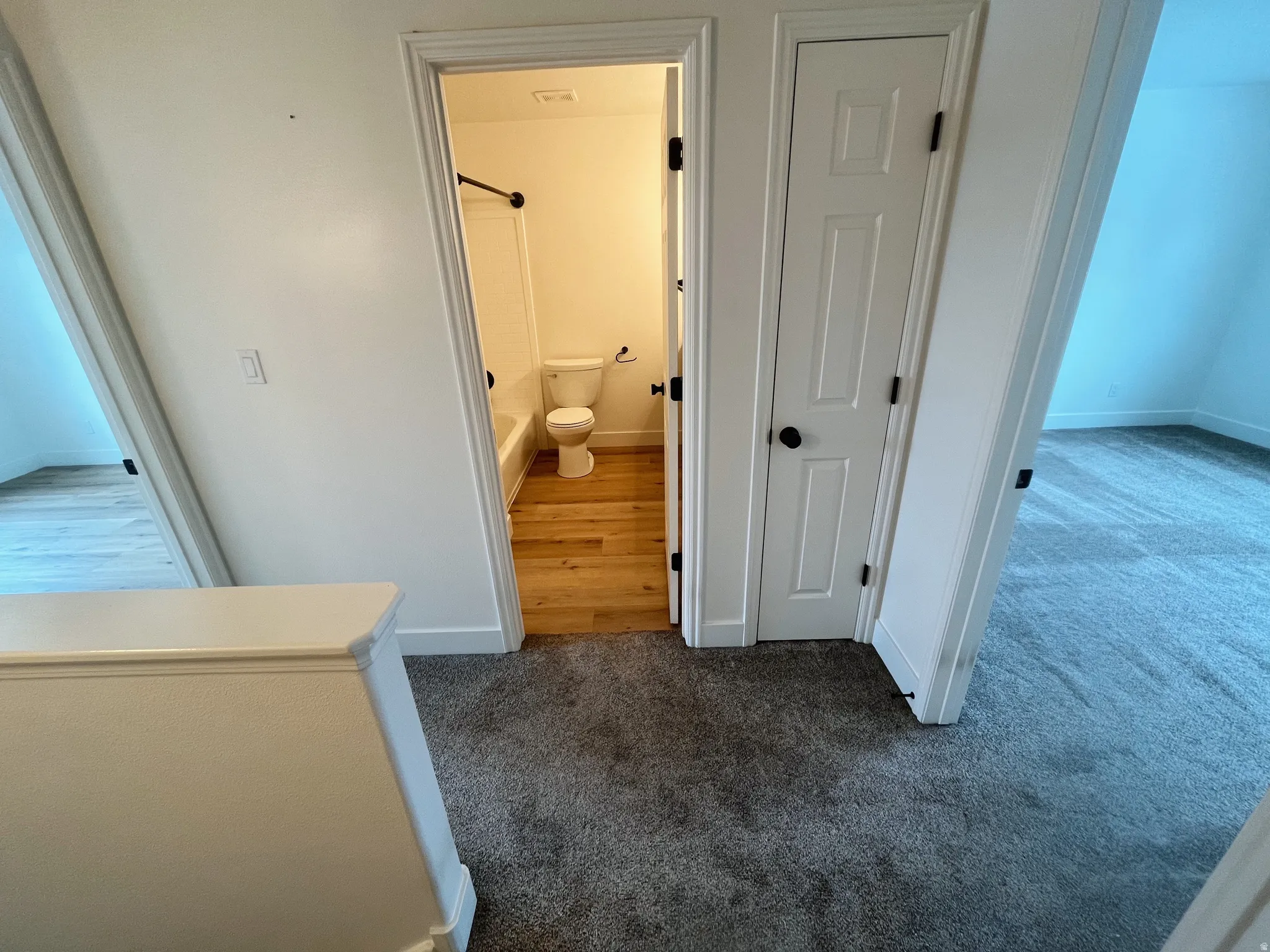 Central hallway with plush gray carpeting and white painted banister