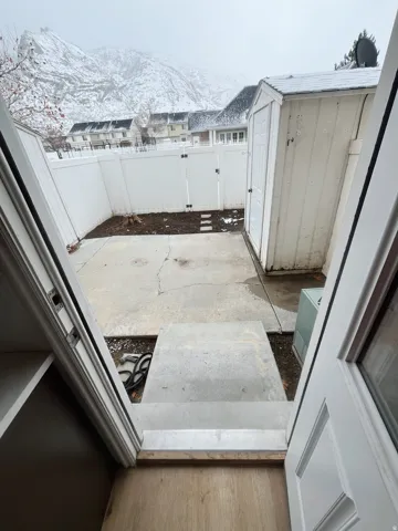 Private concrete patio area featuring a storage shed and white privacy fencing