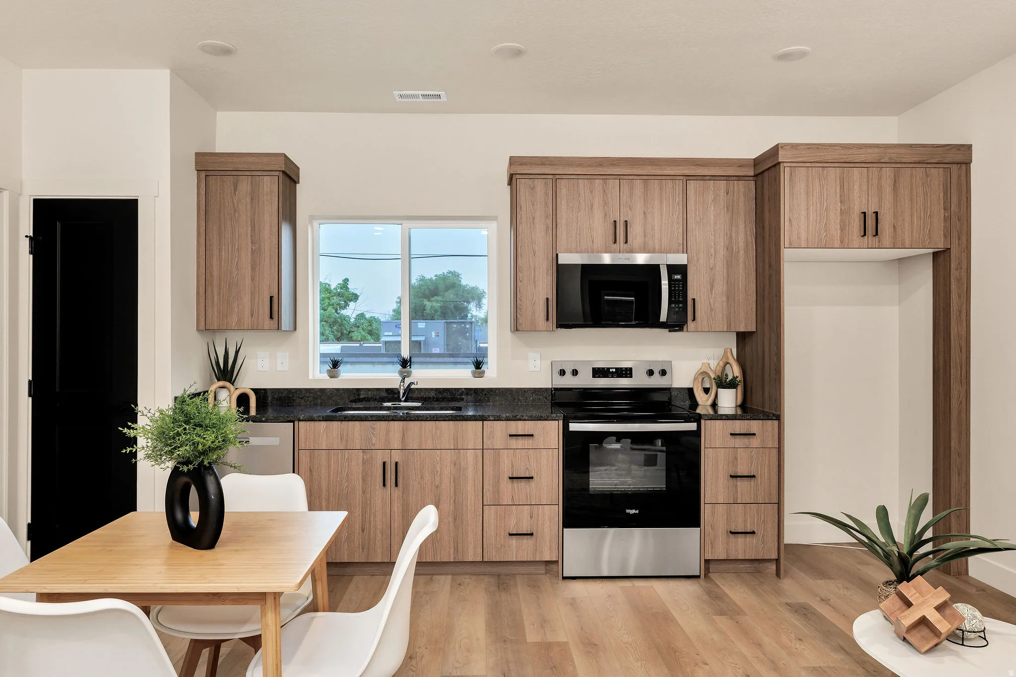Modern kitchen featuring wood-finish cabinetry, dark granite countertops, and stainless steel appliances
