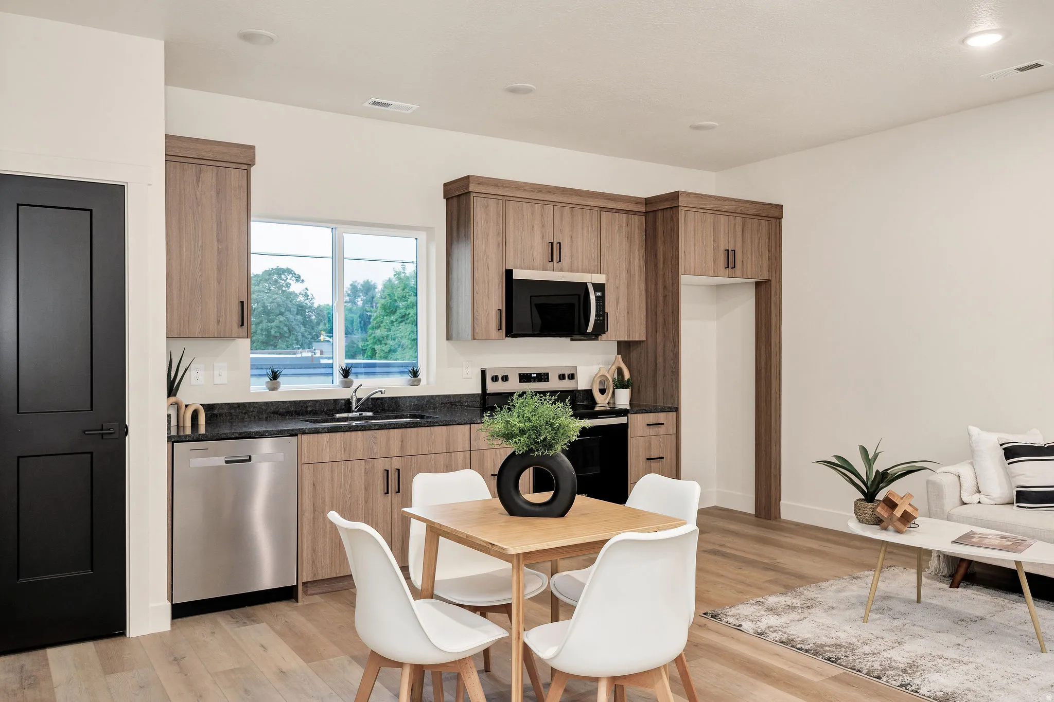 Open-concept kitchen and living area featuring wood-finish flooring, recessed lighting, and a black paneled door