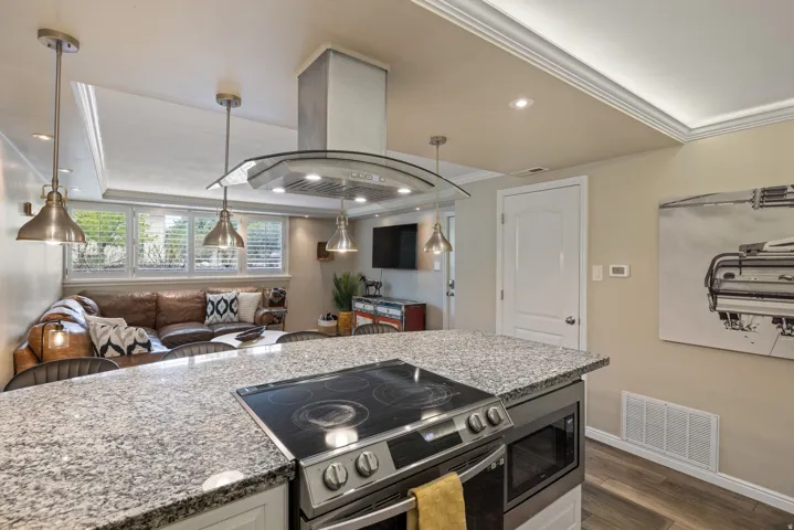 Kitchen island with a built-in electric range, integrated microwave, and speckled countertop